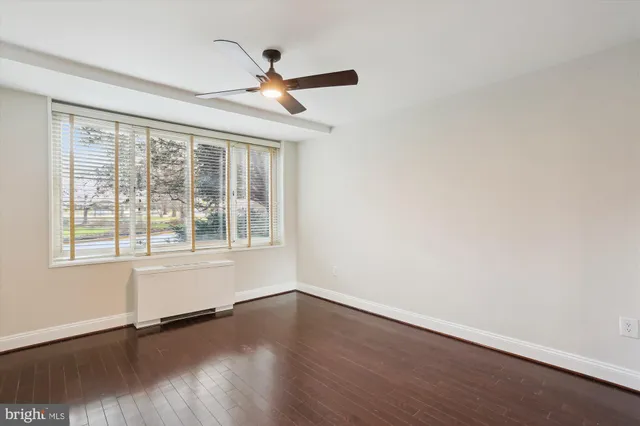 an empty room with wooden floor fan and windows