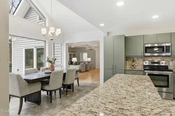 a dining room with wooden floor a chandelier a wooden table and chairs