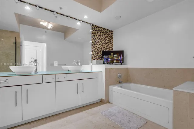 a bathroom with a double vanity sink a large mirror and a bathtub