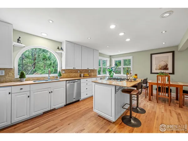 a kitchen with a refrigerator a stove a sink dishwasher with a dining table and chairs with wooden floor