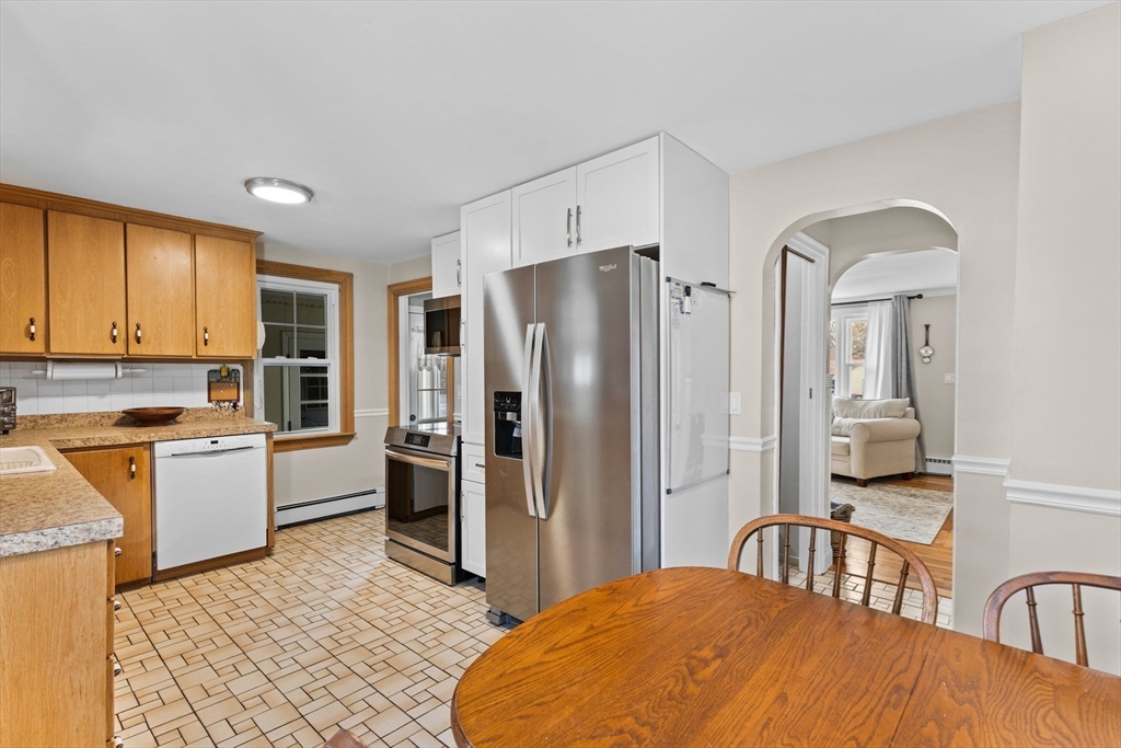 13 Cherry Hill Drive Seekonk, MA 02771 - Photo 8 of 40 a kitchen with stainless steel appliances granite countertop a refrigerator a stove a sink a dining table and chairs with wooden floor