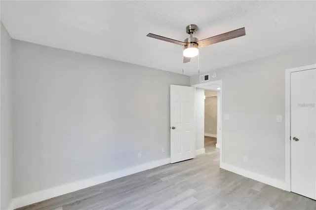an empty room with wooden floor ceiling fan and window
