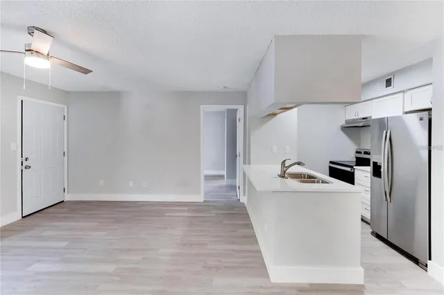 a view of a kitchen with a sink refrigerator and wooden floor