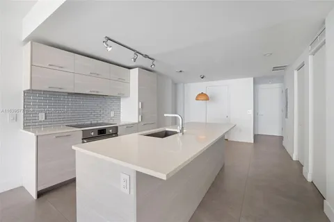 a kitchen with stainless steel appliances a white refrigerator stove a sink and white cabinets