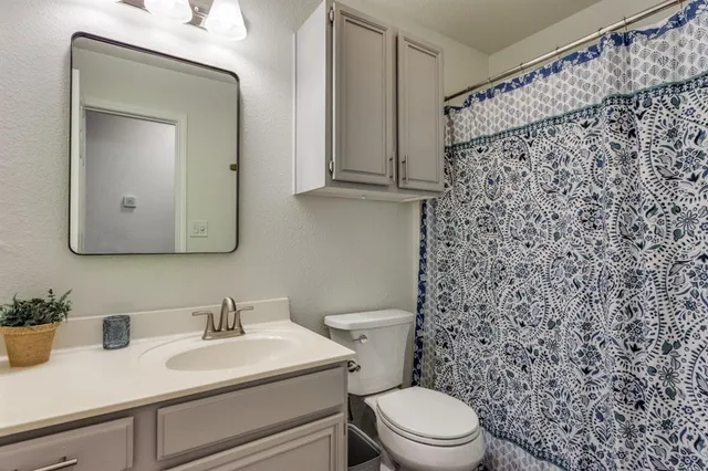 a bathroom with a toilet sink vanity and mirror