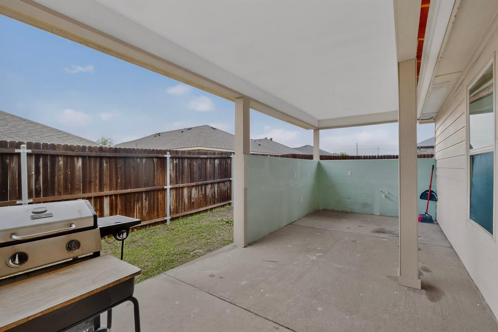 1409 Slate Street Princeton, TX 75407 - Photo 34 of 36 Covered concrete patio with a painted privacy wall and direct access to a grassy yard