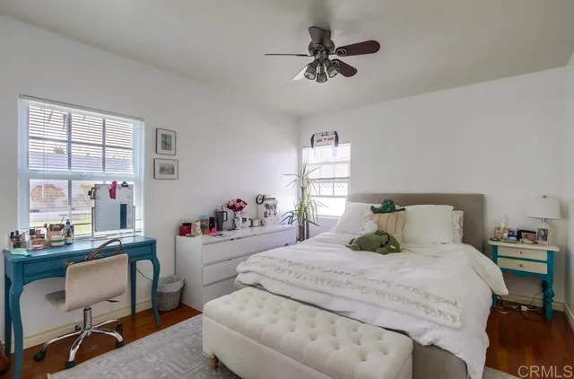 a bedroom with a bed a desk and chair with window