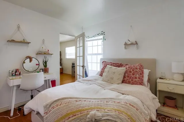 a bedroom with a bed a clock on table and a large window