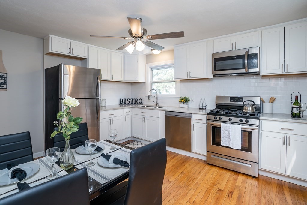 a kitchen with stainless steel appliances kitchen island granite countertop a sink dishwasher stove and refrigerator with wooden floor