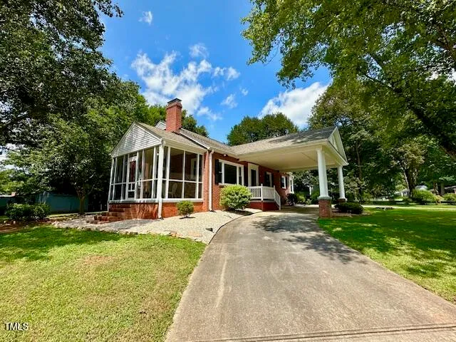 a front view of house with yard slide and large trees