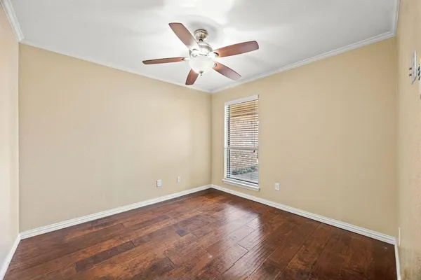 an empty room with wooden floor fan and windows