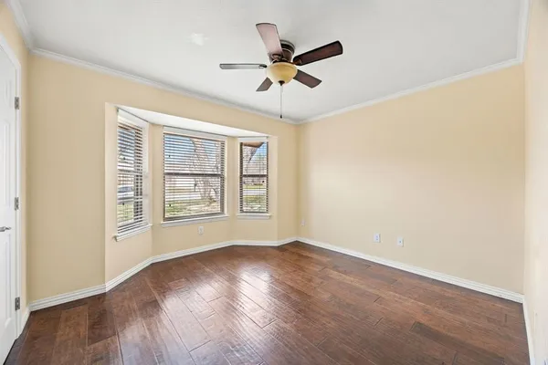 an empty room with wooden floor fan and windows