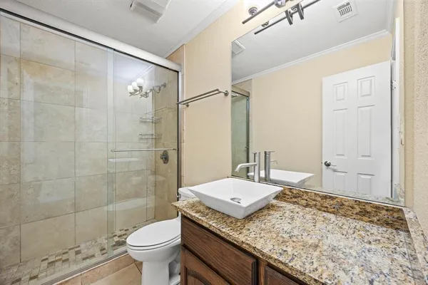 a bathroom with a granite countertop sink a toilet a mirror and shower