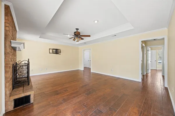 a view of an empty room with wooden floor and a ceiling fan