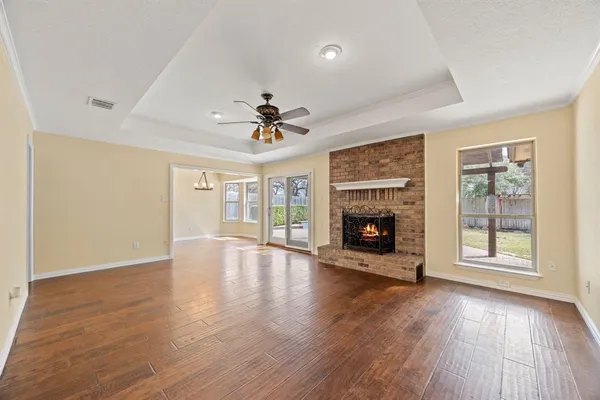a view of an empty room with wooden floor fireplace and a window