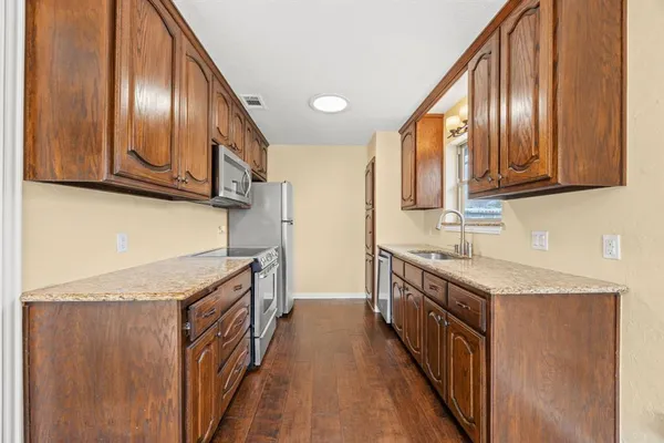 a kitchen with granite countertop stainless steel appliances a sink stove top oven and cabinets