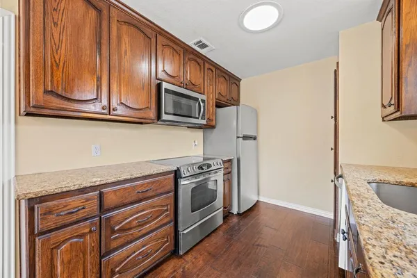 a kitchen with granite countertop stainless steel appliances a stove microwave and refrigerator