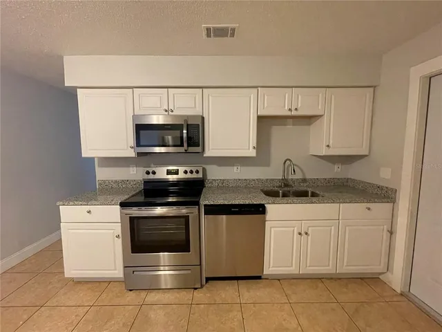 a kitchen with stainless steel appliances granite countertop a stove a sink and a microwave