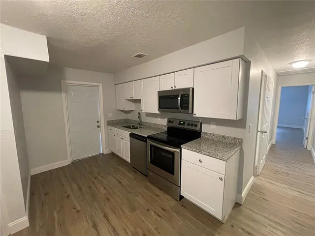 a kitchen with a sink a microwave a refrigerator and cabinets