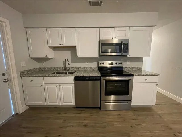 a kitchen with kitchen island granite countertop a stove and a sink