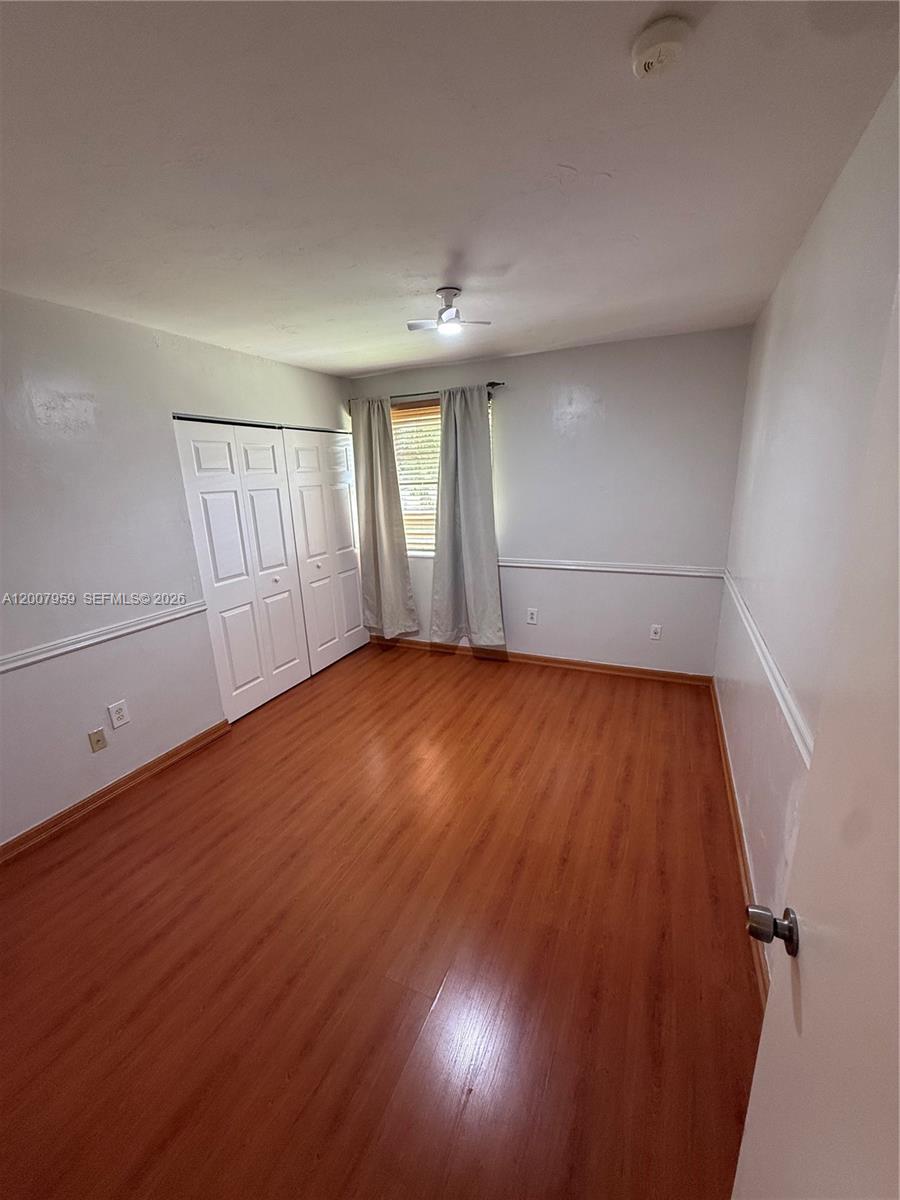 10661 Southwest 113th Place, Unit 94B Miami, FL 33176 - Photo 38 of 54 an empty room with wooden floor and windows