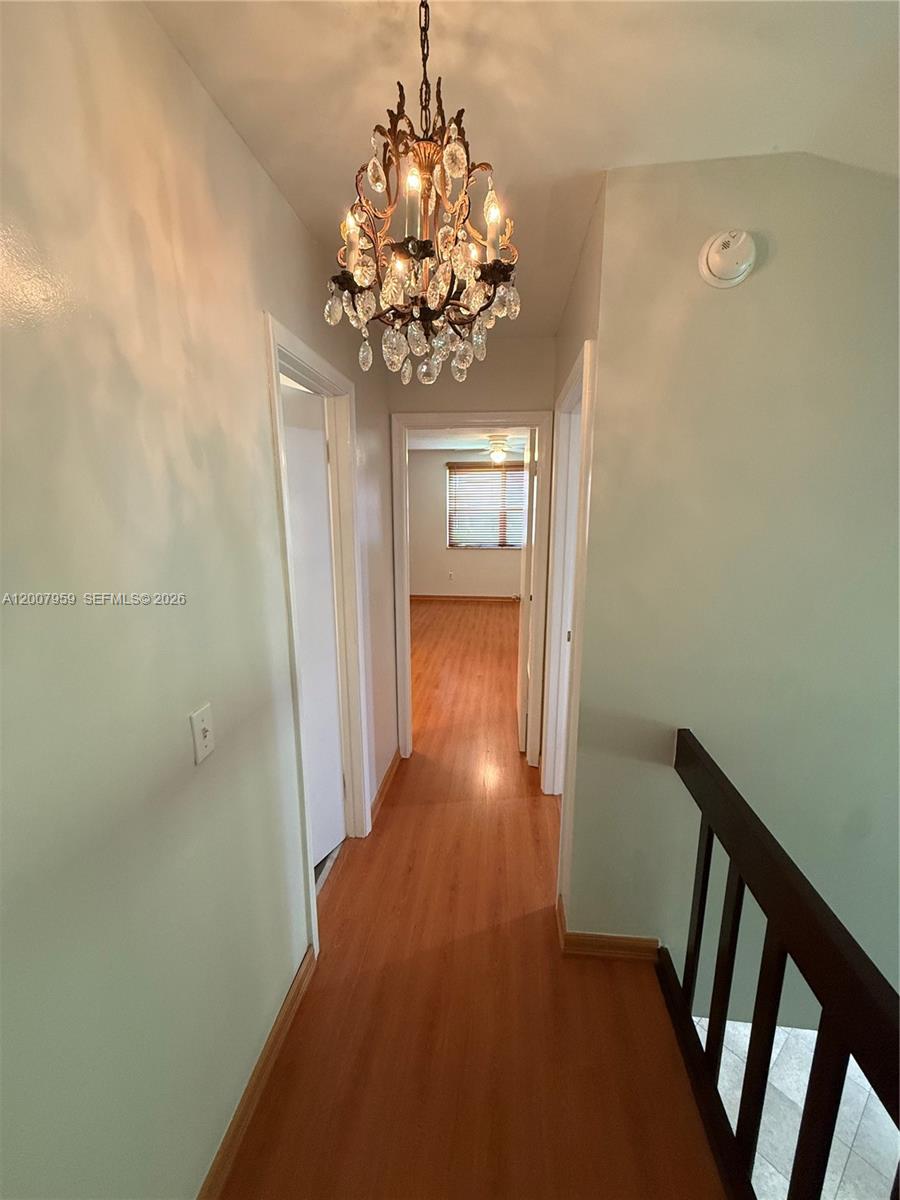 10661 Southwest 113th Place, Unit 94B Miami, FL 33176 - Photo 39 of 54 a view of a hallway with wooden floor and chandelier