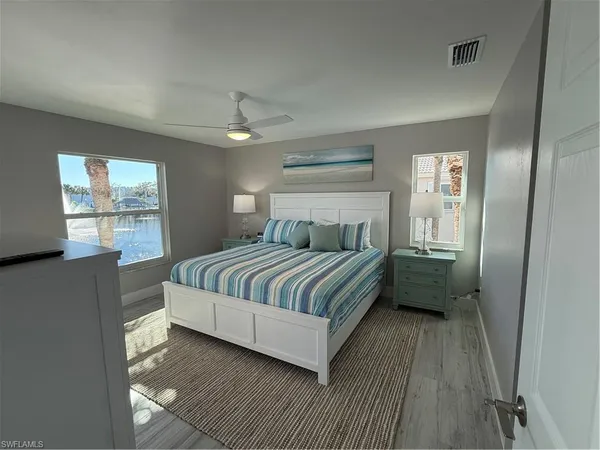 a bedroom with a large bed a chandelier and windows