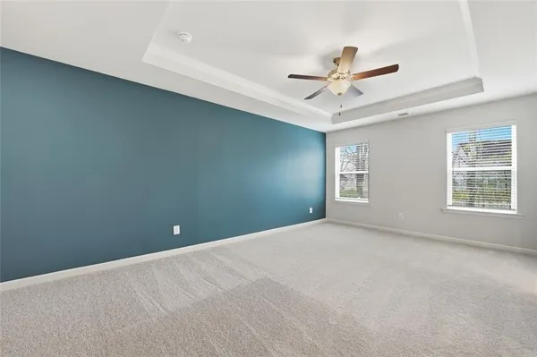 an empty room with chandelier fan and windows