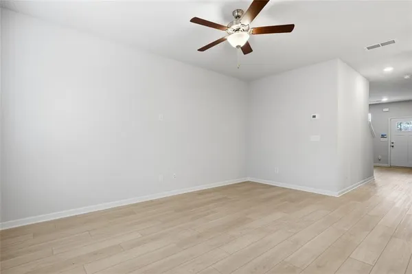 an empty room with wooden floor and fan