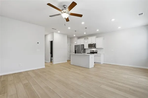 a view of kitchen with kitchen island stainless steel appliances refrigerator stove top oven and cabinets