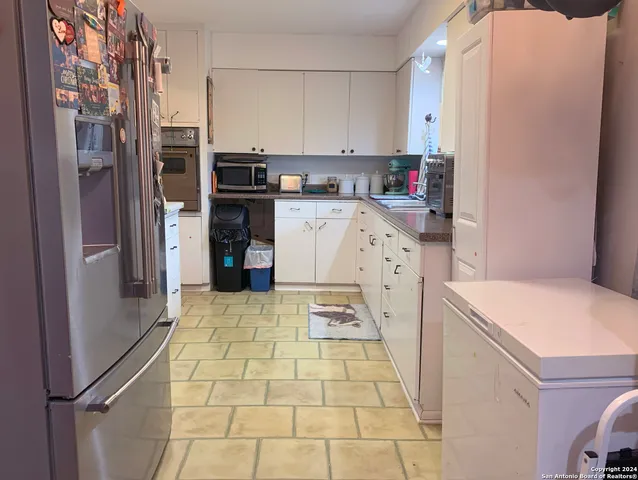 a kitchen with stainless steel appliances a refrigerator sink and white cabinets
