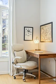 a view of a workspace with furniture and a window