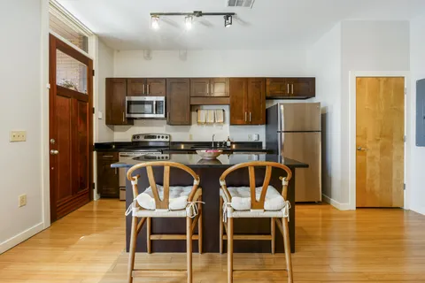 a kitchen with stainless steel appliances granite countertop a refrigerator a stove a sink dishwasher and white cabinets with wooden floor