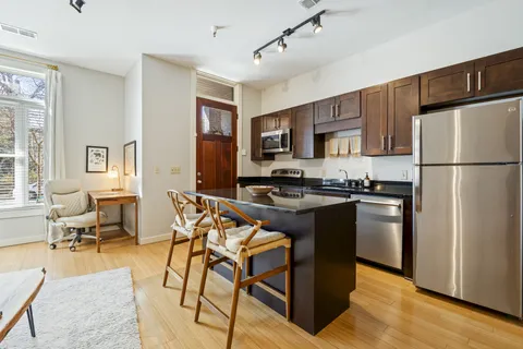 a kitchen with stainless steel appliances granite countertop a refrigerator a stove a sink dishwasher and a refrigerator with wooden floor