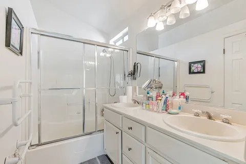 a bathroom with a double vanity sink mirror and shower