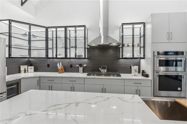 a large white kitchen with granite countertop a sink white cabinets and stainless steel appliances