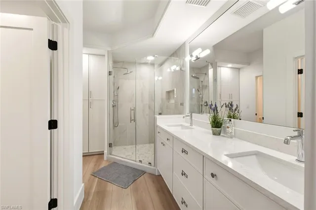 a bathroom with a sink double vanity granite tub shower and a mirror