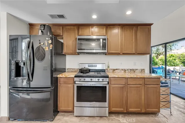 a kitchen with stainless steel appliances granite countertop a stove a refrigerator and a microwave