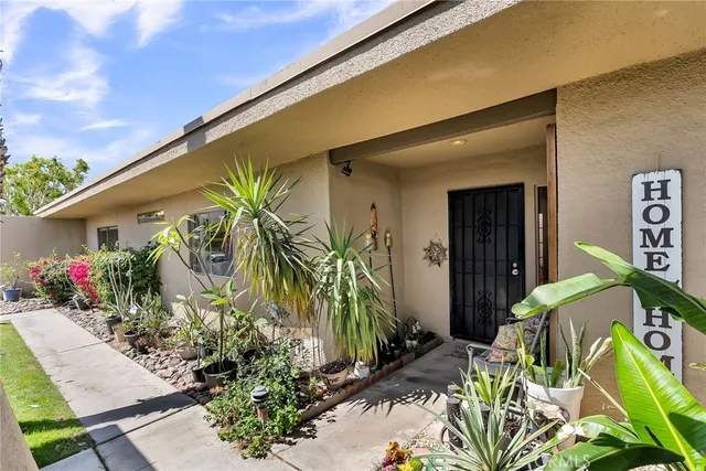 a front view of yellow house with a flower garden