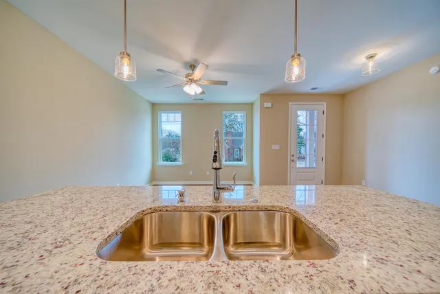 a view of a kitchen with kitchen island a sink wooden floor and stainless steel appliances