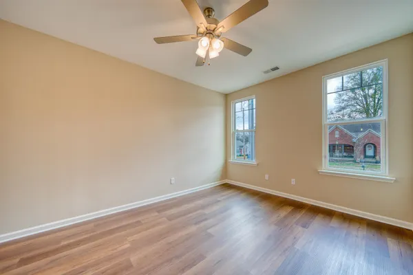 a view of an empty room with window and wooden floor