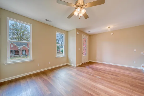 a view of an empty room with window and wooden floor