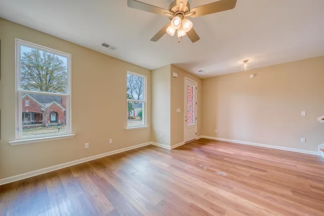 a view of an empty room with window and wooden floor