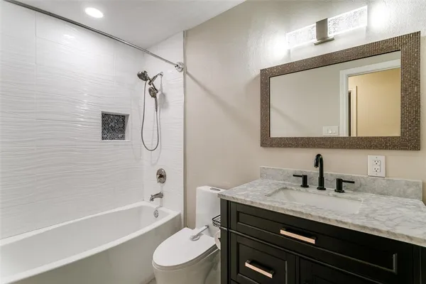 a bathroom with a granite countertop sink a toilet a mirror a vanity and shower