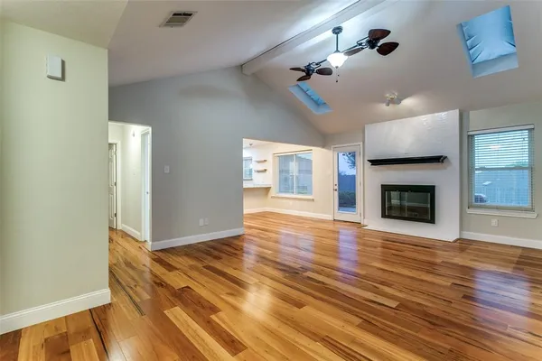 a view of an empty room with wooden floor fireplace and a window