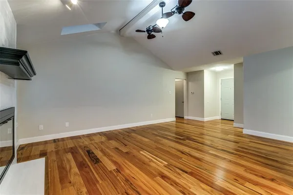 a view of an empty room with a window and a chandelier fan