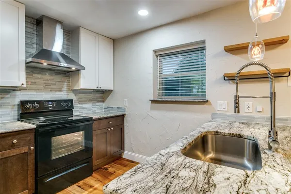 a kitchen with granite countertop a sink stove and cabinets