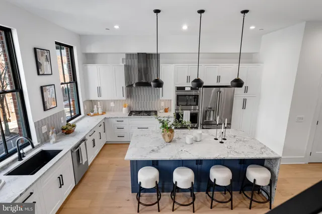 a view of kitchen island with stainless steel appliances kitchen island granite countertop a table chairs in it and wooden floors