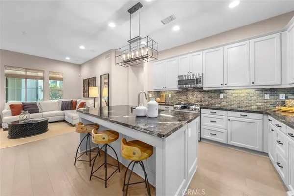 a kitchen with stainless steel appliances granite countertop a table chairs sink and cabinets