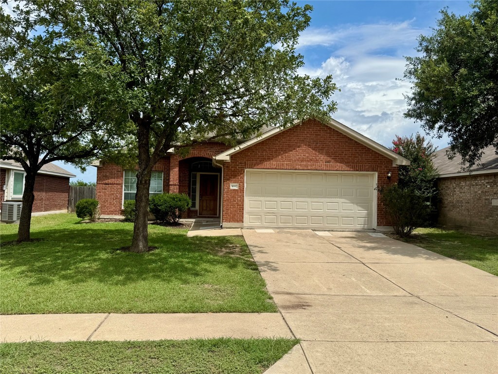 View of front facade featuring an attached garage, brick siding, and driveway